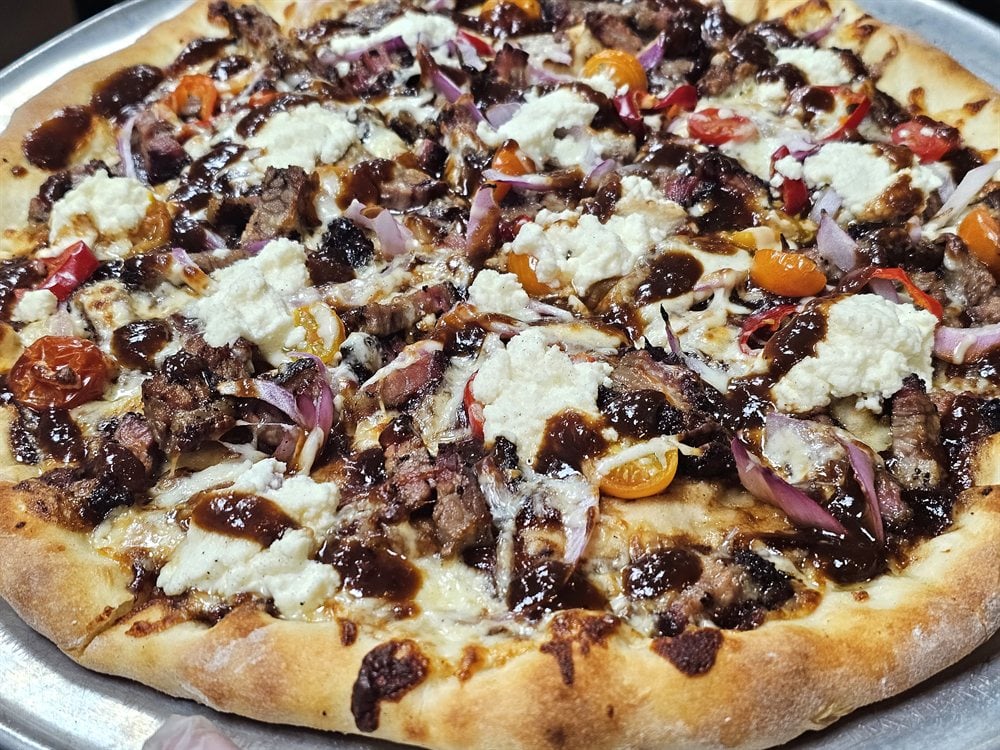 Eager Beaver BBQ artisan pizza — smoked brisket, ricotta, cherry tomatoes, and BBQ drizzle